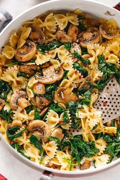 pasta with mushrooms and spinach in a white bowl