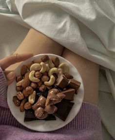 a person is holding a plate with nuts and chocolate on it in the middle of their stomach