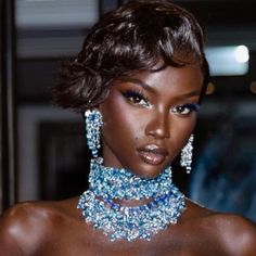 a woman with short hair wearing blue jewelry