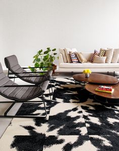 a living room filled with furniture and a rug on top of a hard wood floor