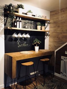 a wooden desk with two stools next to it and shelves on the wall behind it