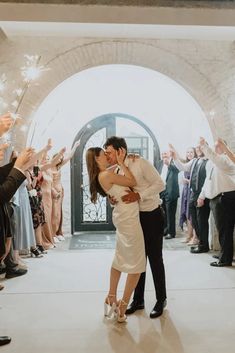 a newly married couple kissing in front of their guests and sparklers at the end