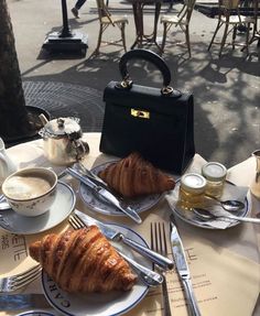 a croissant and coffee are on the table at an outdoor cafe in paris