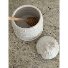 a white cup with a wooden spoon in it next to a container on a counter