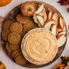 a plate with cookies, apples and an apple dip on it next to some pumpkins