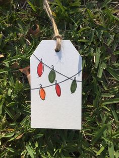 a white tag hanging from a string with red, green and orange lights on it