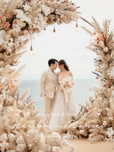 a bride and groom standing in front of a floral arch at their wedding ceremony on the beach