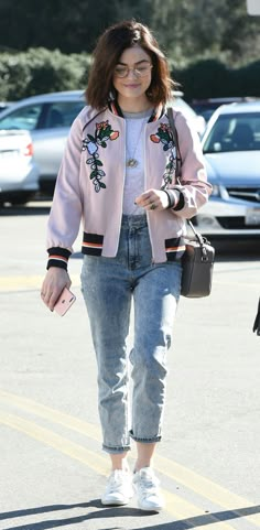 a woman walking across a parking lot holding a purse