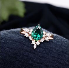 an emerald colored ring with white diamonds on it