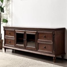 a large wooden entertainment center in a living room with white walls and rugs on the floor