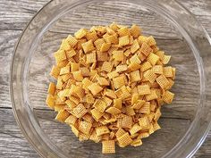 a glass bowl filled with cheetos on top of a wooden table