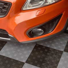 an orange sports car parked on a black and white checkered floor