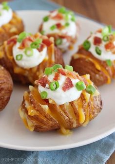 several baked potatoes topped with cheese and green onions