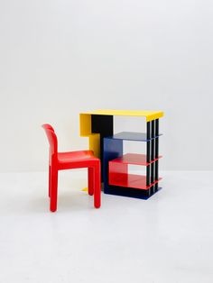 two chairs and a table made out of different colored blocks on a white surface with one chair facing the other