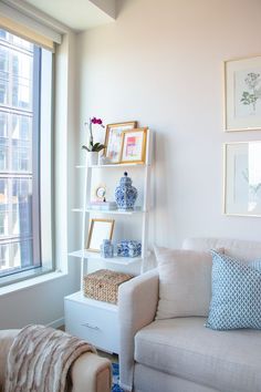 a white couch sitting next to a window in a living room with pictures on the wall