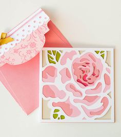 a card with a pink flower on it next to an envelope and some other items