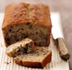 a loaf of banana bread sitting on top of a cutting board next to a knife