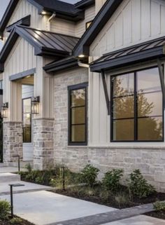 an exterior view of a home with stone and brick sidings, windows, and landscaping