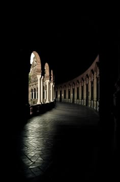 an empty walkway in the dark with arches