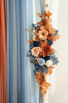 a bouquet of flowers is hanging on the wall next to a blue and white curtain