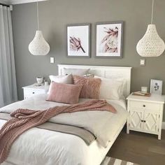 a white bed sitting in a bedroom next to two pictures hanging on the wall above it