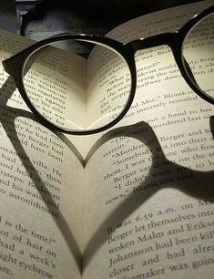 the shadow of a heart shaped book with glasses on it