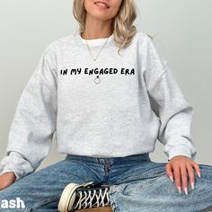 *If you would like a colour or size that is not listed, please contact us. The In My Engaged Era Sweatshirt is perfect for newly engaged individuals ready to shout their love from the rooftops! This fun and stylish tee is a great way to celebrate your new chapter. Whether you're announcing your engagement, planning wedding details, or enjoying your time as a fiancé, this shirt is here to capture the magic of this special era. 💍💖 🎨 Design Highlights: Fun "In My Engaged Era" text design with a modern, trendy font that stands out 🖋💫 Soft, high-quality fabric that feels comfortable and cozy--ideal for engagement parties, bridal showers, or lounging while planning your big day 👕💖 Available in a variety of romantic colors and sizes to match your style, from XS to 3XL 🌈👚 Unisex design, m Engagement Planning, Fiance Sweatshirt, Plus Size Hoodie, Trendy Fonts, Engagement Parties, Planning Wedding, Romantic Colors, Engagement Announcement, Newly Engaged