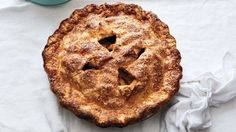 an apple pie on a white tablecloth next to a blue potted planter