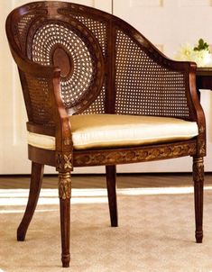 a wooden chair sitting on top of a carpeted floor next to a table with a lamp