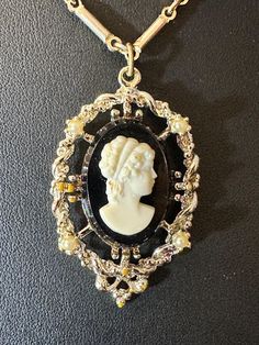 Vintage, unmarked JUDY LEE black and white cameo pendant in fancy goldtone frame. 16" goldtone chain is not the original chain. Lady is not carved.  Good pre-owned condition. This listing contains photographs of the actual item you will receive. Please look closely at the pictures in this listing as they are part of the product description. Please read the description, as any imperfections or condition comments will be included.  I urge you to please contact me with any and all questions. I am happy to provide more photos of the item on request. I'm still a newbie and getting the hang of photographing jewelry. Photographing Jewelry, Cameo Pendant, Jewelry Necklace Pendant, Gold Tones, Im Not Perfect, Jewelry Necklaces, Product Description, Carving, Pendant Necklace