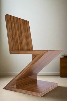 a wooden chair sitting on top of a carpeted floor next to a white wall