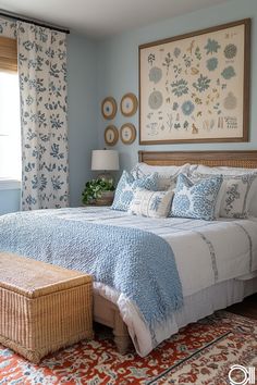 a bed with blue and white comforter in a bedroom next to a painting on the wall