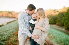 a man and woman holding a baby in their arms while standing next to each other