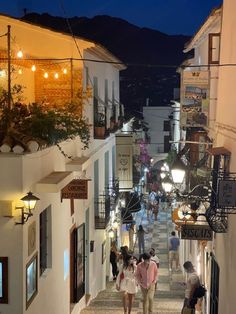 people are walking down an alley way at night