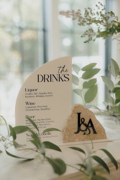 the drinks menu is displayed on a table with greenery and flowers in vases