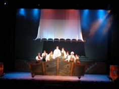 a group of people sitting on top of a boat in the middle of a stage