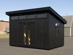 a small black building sitting on top of a parking lot