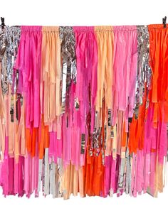 there are many different colored streamers hanging on the wall together, and one is pink, orange, yellow, and silver