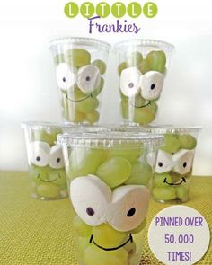 an image of some green apples in plastic cups with googly eyes on them for halloween