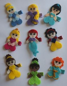 there are many little felt dolls on the table, each with different outfits and hair colors