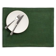 a white plate with two silver forks on top of it next to a green place mat