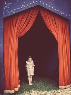 a woman standing in front of a red curtain