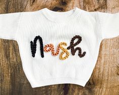 This sweater will be a staple in your tiny human's wardrobe this fall and winter! It's intentionally oversized for that perfect comfy/cozy look and feel. We currently offer a white oversized sweater in 8 different size options and 16 different yarn colors. Embroidery can be completed using one yarn color OR up to four different yarn colors to alternate between letters. These sweaters can be customized with one OR two words. Customization can include, but is not limited to, the traditional and novelty examples below! TRADITIONAL EXAMPLES: One Word: First Name Only (ie. Nash) Two Words: First & Middle Names (ie. Nash Daniel) Double Names (ie. Mary-Kate) NOVELTY EXAMPLES: One Word: Howdy Lucky (St. Patrick's Day) One (Birthday) Gobble (Thanksgiving) Two Words: Merry Christmas Big/Little Bro(t Oversized Embroidered White Sweater, Oversized White Fall Sweater, Oversized White Sweater For Fall, White Oversized Sweater For Fall, Cozy White Cotton Sweater, White Embroidered Knit Sweater, Oversized Cotton Cable Knit Top, Oversized Cable Knit Cotton Top, White Comfortable Fit Sweater For Fall