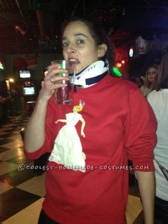 a woman in a red shirt holding a drink and wearing a neck gaitert