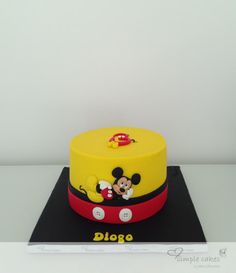 a mickey mouse cake on top of a black and red plate with the name didge