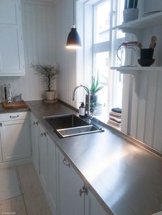 a kitchen with stainless steel counter tops and white cabinets