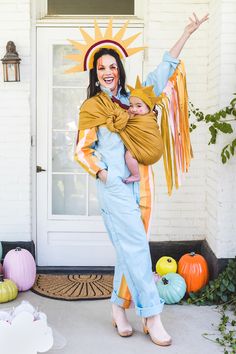 a woman holding a baby in her arms while standing on the front steps of a house