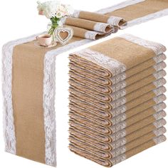 a stack of burlap and lace table runneres with white flowers on top