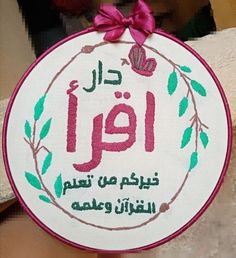 a white and pink embroidered sign with arabic writing on it's side, in front of a brick wall