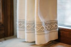 two white towels sitting on top of a window sill next to a wooden frame